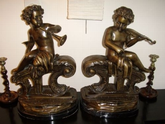 PAIR OF BRONZE CHERUB MUSICIANS SITTING ON PLYNTHS SUPPORTED BY DOLPHINS