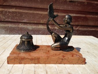 Art-deco marble based ink well with an exotic figure of a woman knelling holding a bird in front of a domed shaped ink well with glass liner.