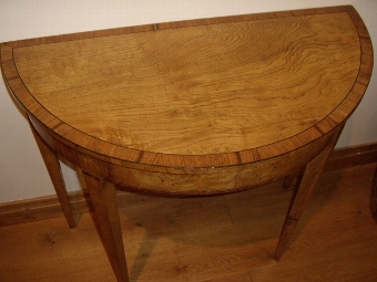 Antique A PAIR OF FINE REGENCY DESIGN DEMI-LUNE CONSOLE TABLES VENEERED IN FINELY CRAFTED YEW,SATINWOOD,MAHOGANY AND BURR-WALNUT HAVING EBONY STRINGING & CHERRYWOOD INLAY & STANDING ON TAPERED LEGS 