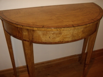 Antique A PAIR OF FINE REGENCY DESIGN DEMI-LUNE CONSOLE TABLES VENEERED IN FINELY CRAFTED YEW,SATINWOOD,MAHOGANY AND BURR-WALNUT HAVING EBONY STRINGING & CHERRYWOOD INLAY & STANDING ON TAPERED LEGS 