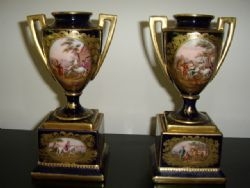 A PAIR OF MINATURE HAND PAINTED CONTINENTAL VASES WITH GILT HANDLES