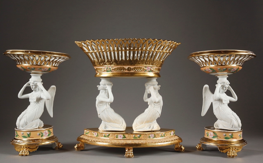 A French Restauration bisque and porcelain table set with three openwork baskets and winged women