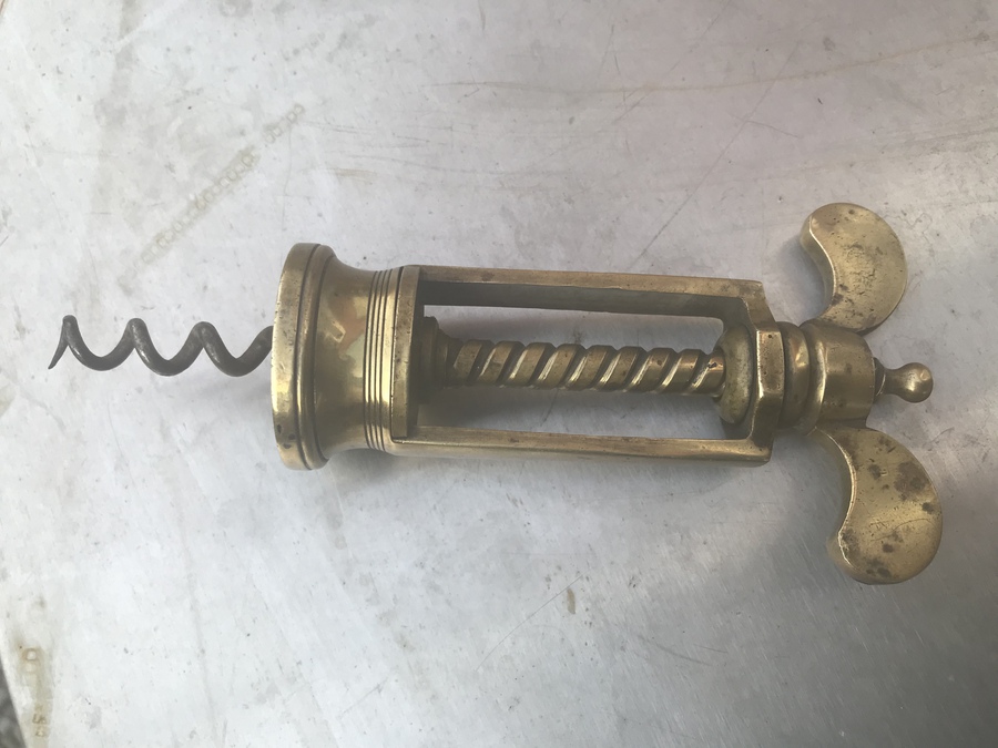 vintage hand made solid brass corkscrew on a natural wood and