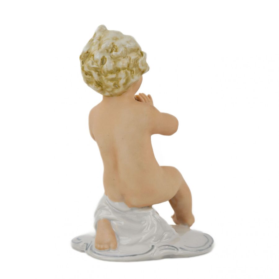 Antique A figurine of a putti playing music on a pipe.