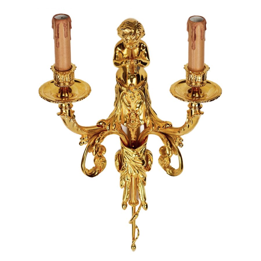 Antique A pair of gilded sconces, with currency curls, surmounted by cherubs.