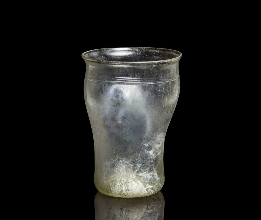 A Roman glass beaker with indented sides