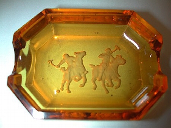 An amber glass polo ashtray with two polo figures
